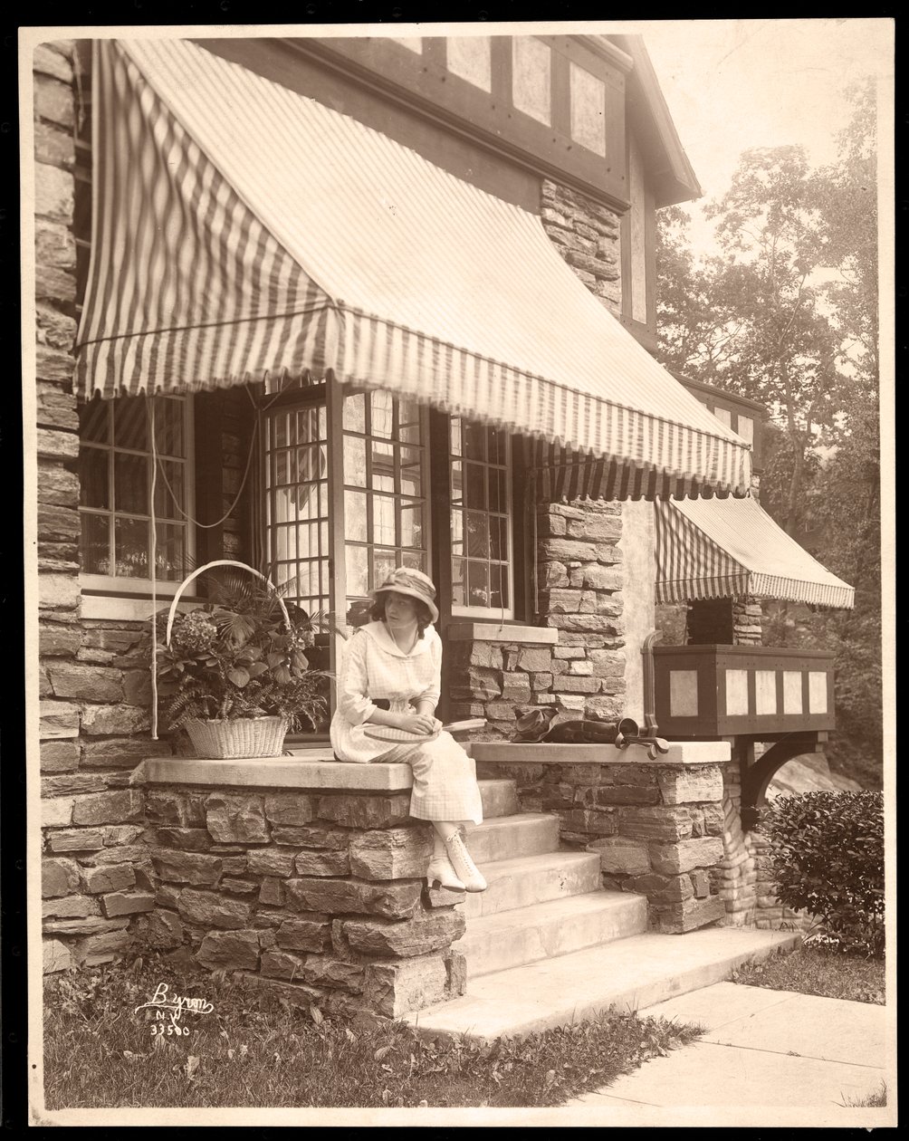 Eine Frau sitzt am Eingang eines Hauses, 1915 von Byron Company