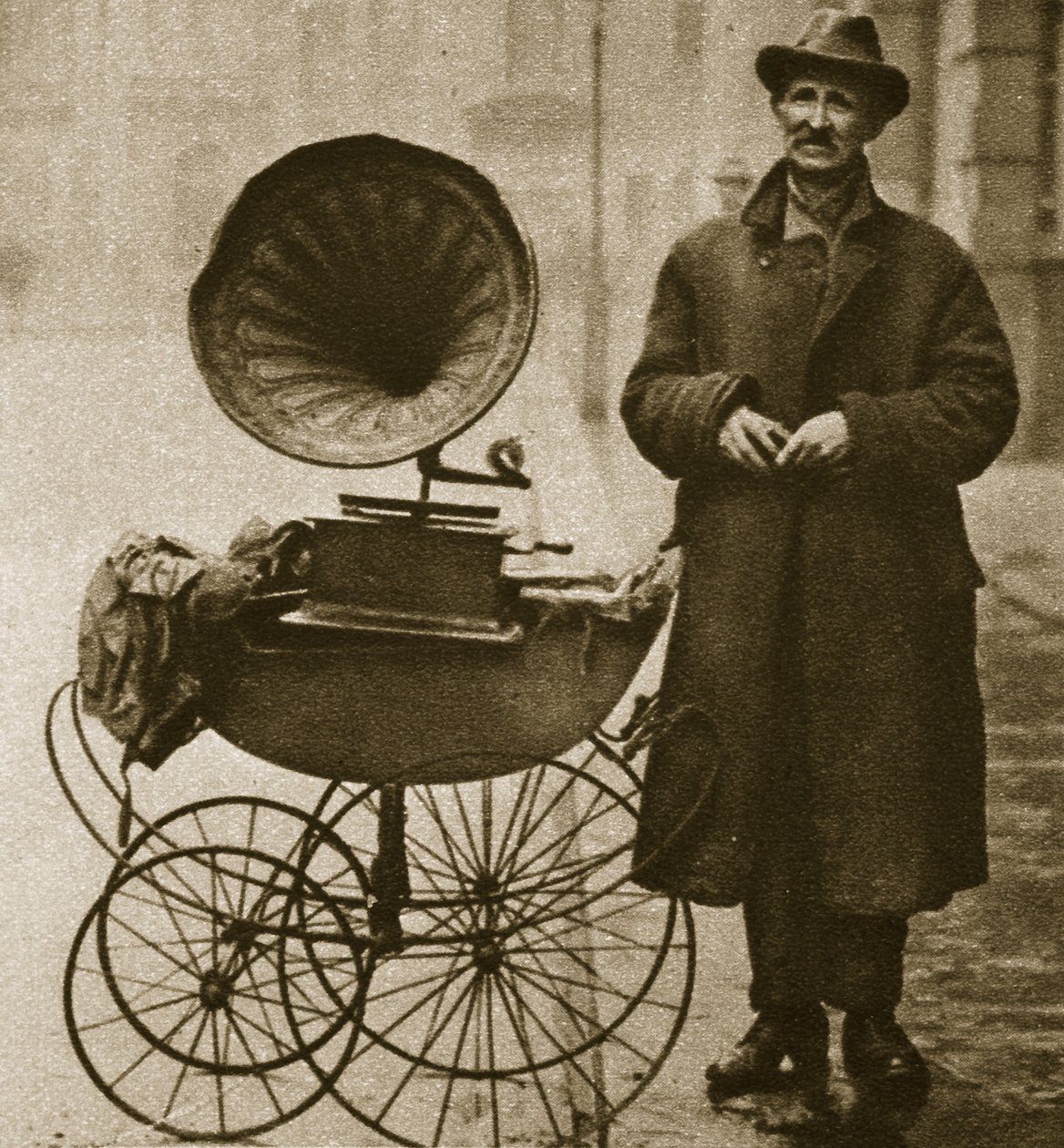 Ein Straßenhändler unterhält mit einem Grammophon, transportiert in einem Kinderwagen von English Photographer