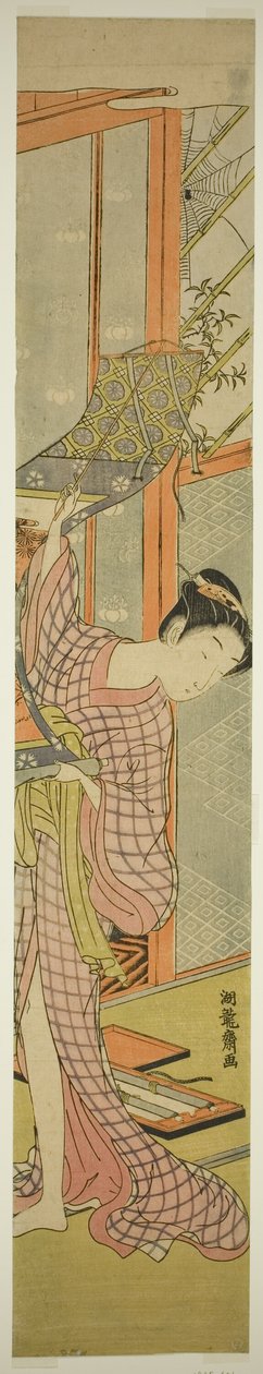 Junge Frau hängt ein Gemälde auf von Isoda Koryusai