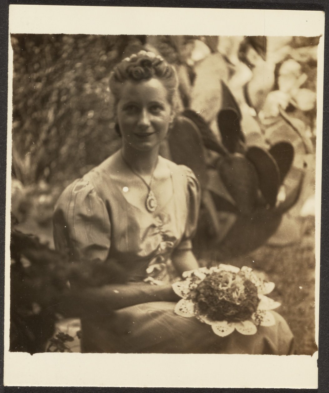 [Frau mit Blumenstrauß vor Kaktus sitzend] von Louis Fleckenstein